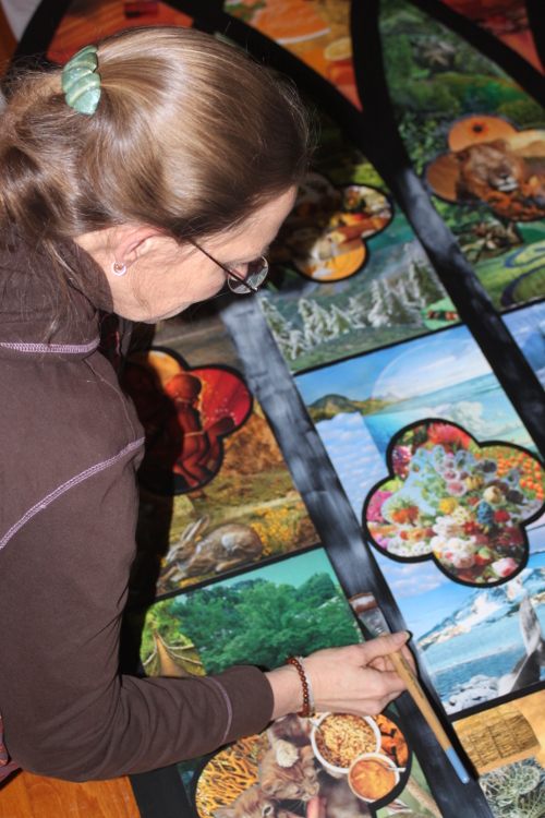 Magazine pages have been cut and collaged onto their pattern pieces, now they are being glued to the background.